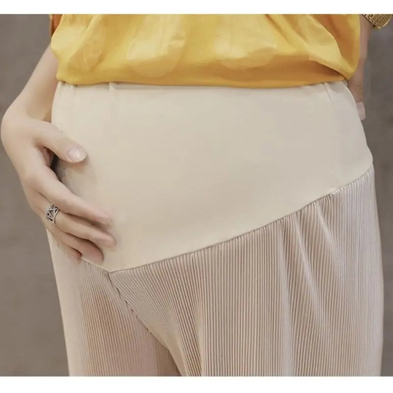 Close-up of a woman wearing breathable adjustable waist maternity pants in summer, showcasing pleated design and comfort for expecting mothers.