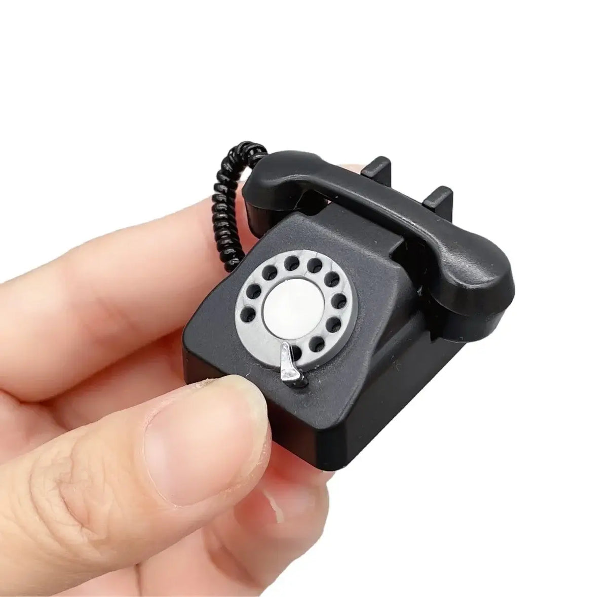 Miniature black rotary phone being held, perfect for photography props or collectibles.