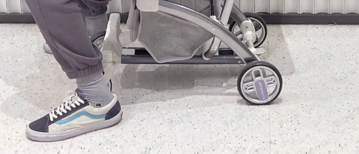 Close-up of an outdoor lightweight stroller wheel and footwear on a smooth floor.