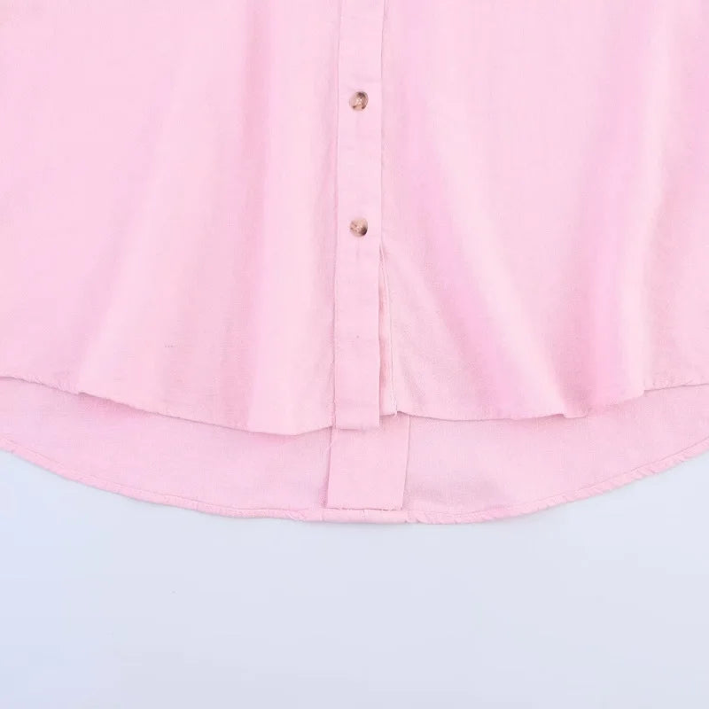 Close-up of a pink oversized button-up shirt, showcasing its soft fabric and curved hemline.
