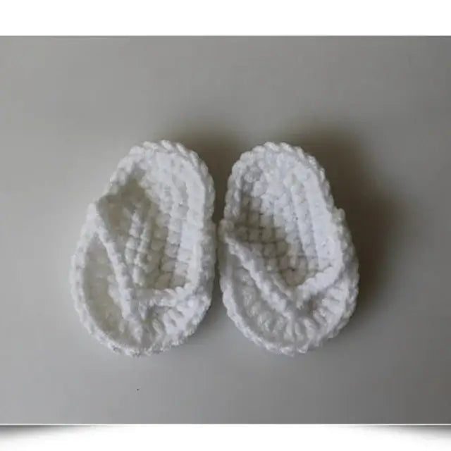 White baby slippers with a cozy knitted texture, perfect for keeping little feet warm and stylish.