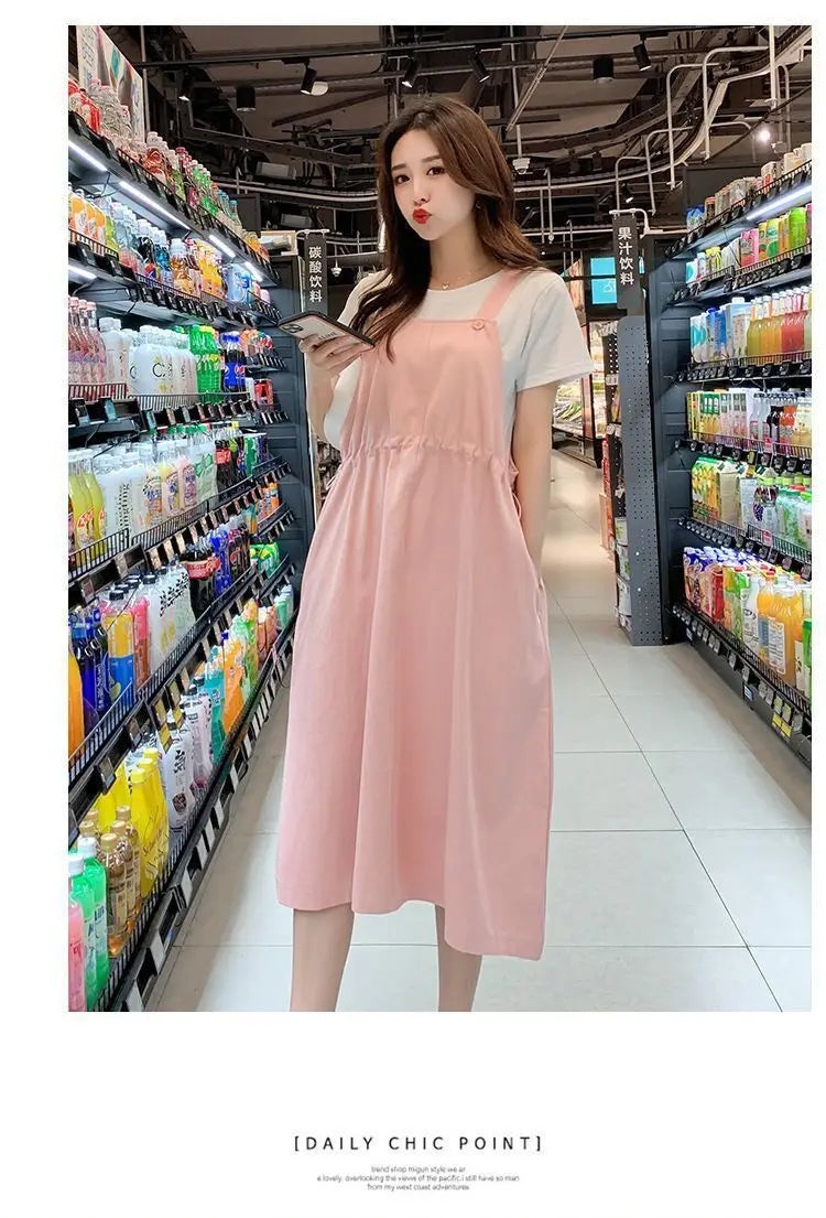 Woman wearing a pink loose fit maternity dress, ideal for casual outings and holiday photography.