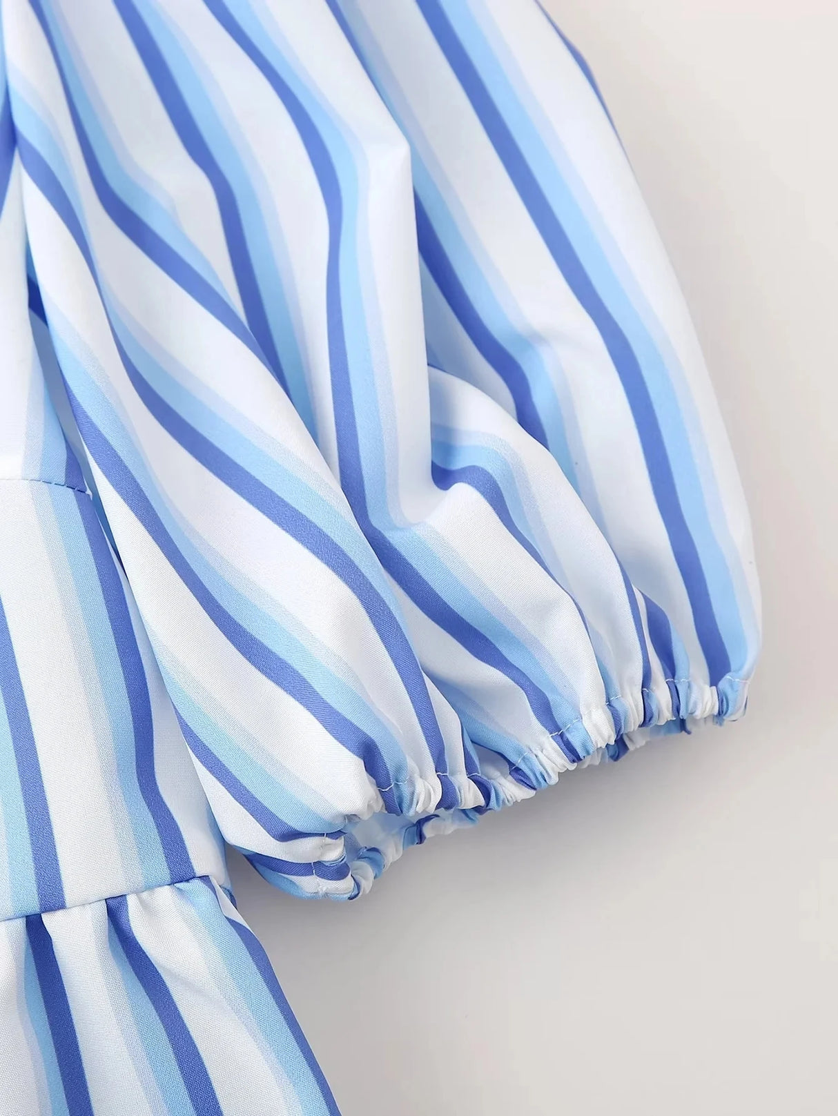 Close-up of blue and white striped fabric showcasing the sleeve detail of the BowChic™ lace-up blouse.