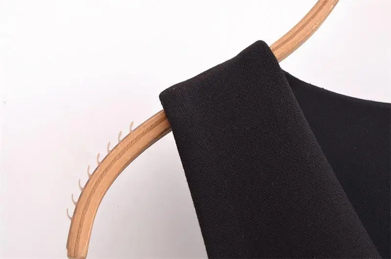 Close-up of a black elegant V-neck women tank top hanging on a wooden hanger.