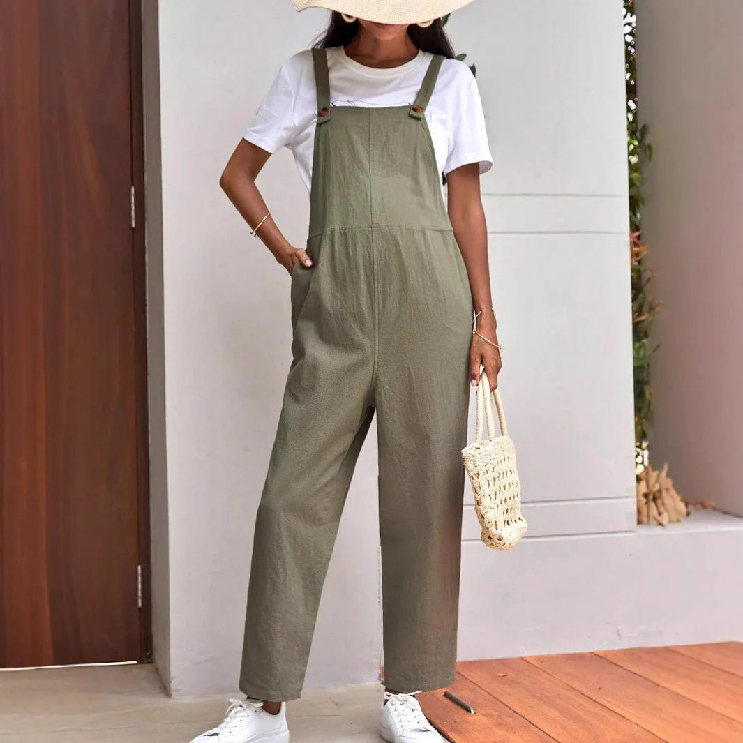 Adjustable maternity overalls in olive green, worn over a white tee, paired with white sneakers and a stylish tote bag.