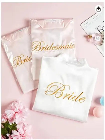 Plus size satin robes for brides and bridesmaids with gold lettering on a pink background.