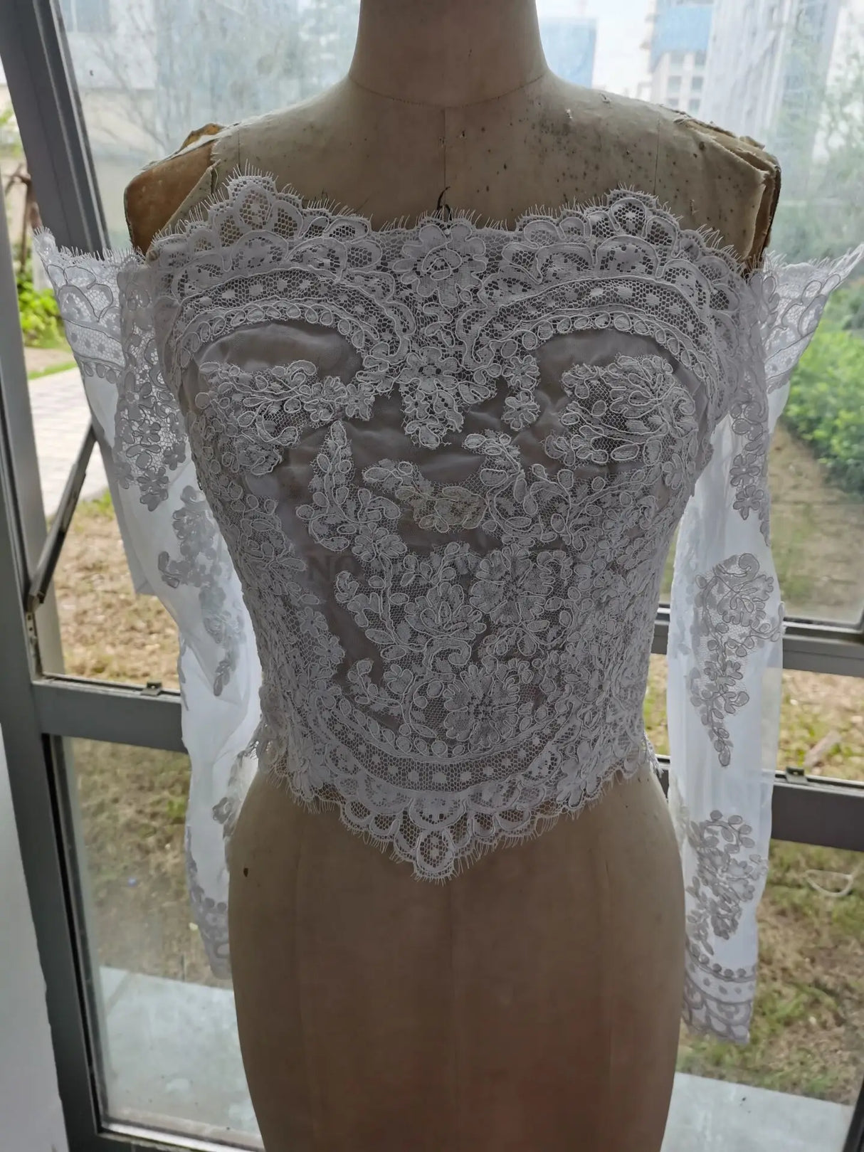 Lace off-shoulder bridal jacket with long sleeves, featuring intricate appliqué design, perfect for weddings.