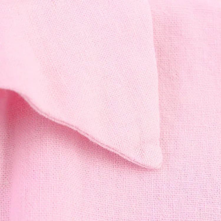 Close-up of light pink linen fabric featuring a soft texture and subtle drape for a stylish look.