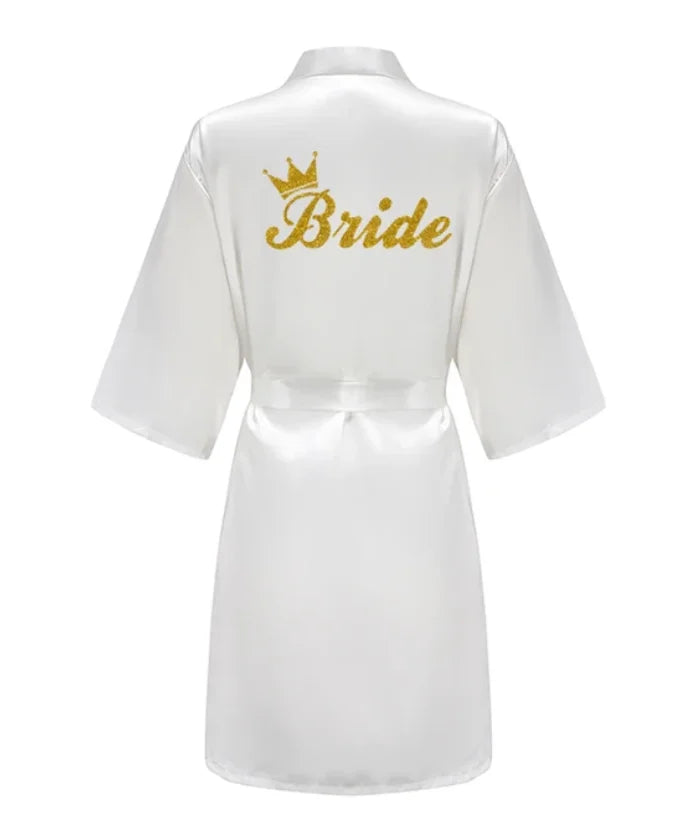 Elegant white satin robe for brides featuring gold glitter 'Bride' text and crown design on the back.
