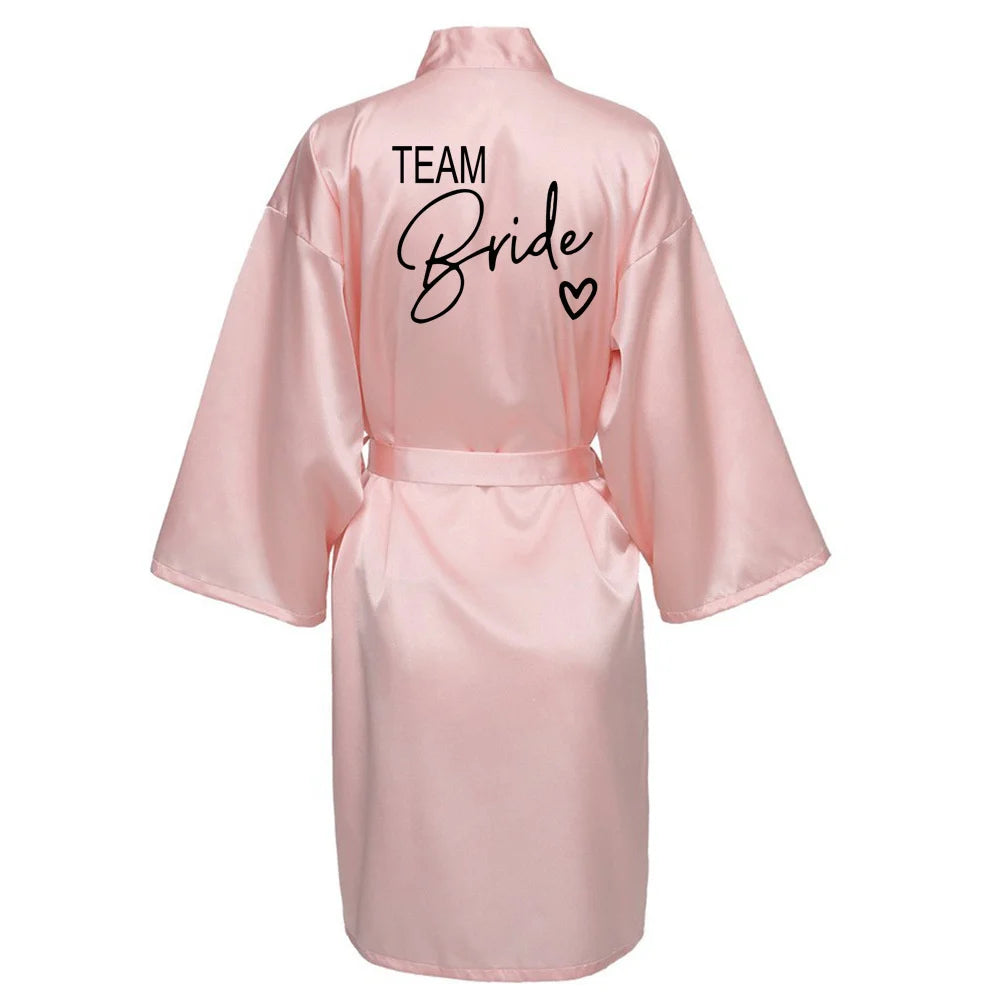 Team Bride pink satin robe with black lettering, perfect for bridal parties and celebrations.