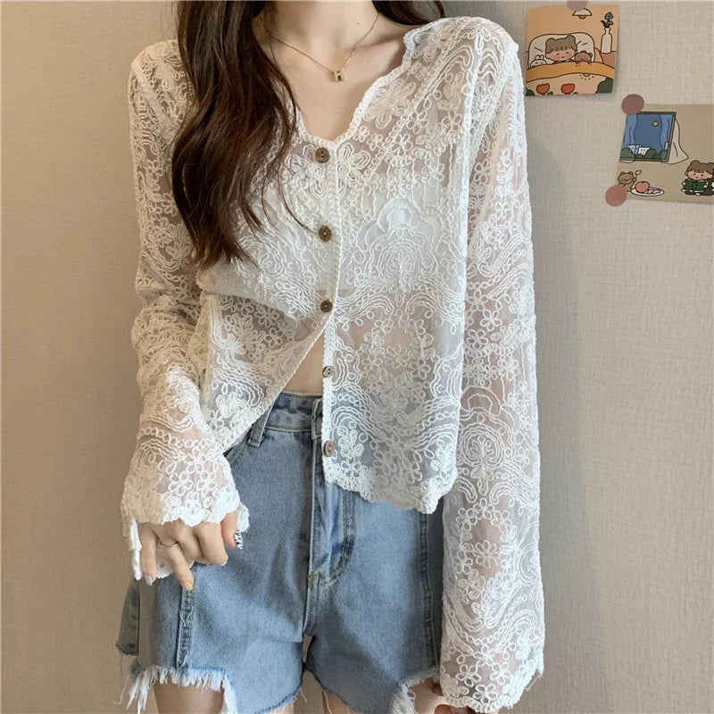 Sheer lace sun shirt with long sleeves and button closure, styled with denim shorts for a sexy summer look.