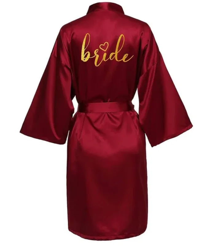 Gold 'bride' lettering on a burgundy satin kimono robe, perfect for wedding celebrations.
