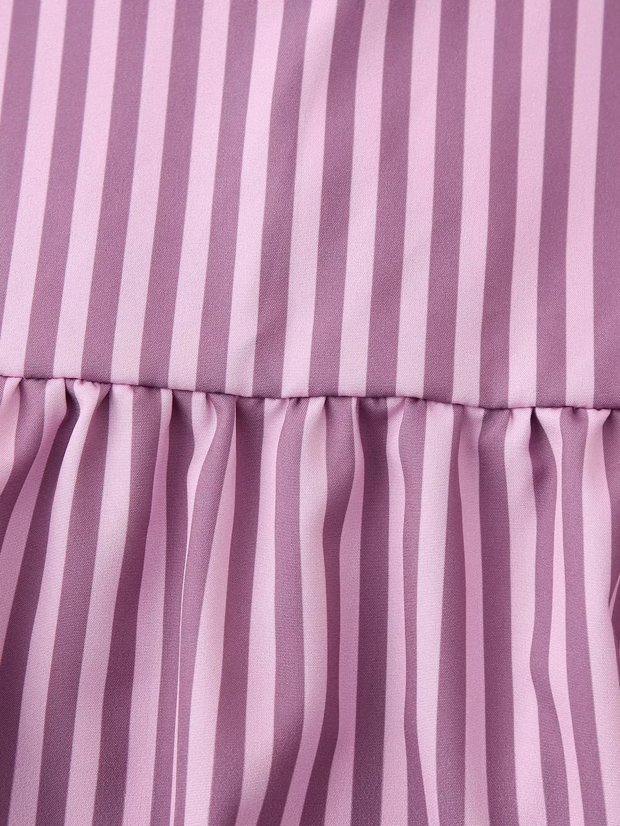 Close-up of a BowChic™ stripe lace-up blouse in soft purple hues featuring vertical stripes and gathered fabric.