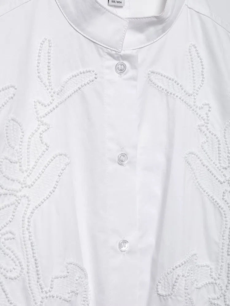 Elegant white embroidery shirt with stand collar and single-breasted closure, showcasing intricate floral details.