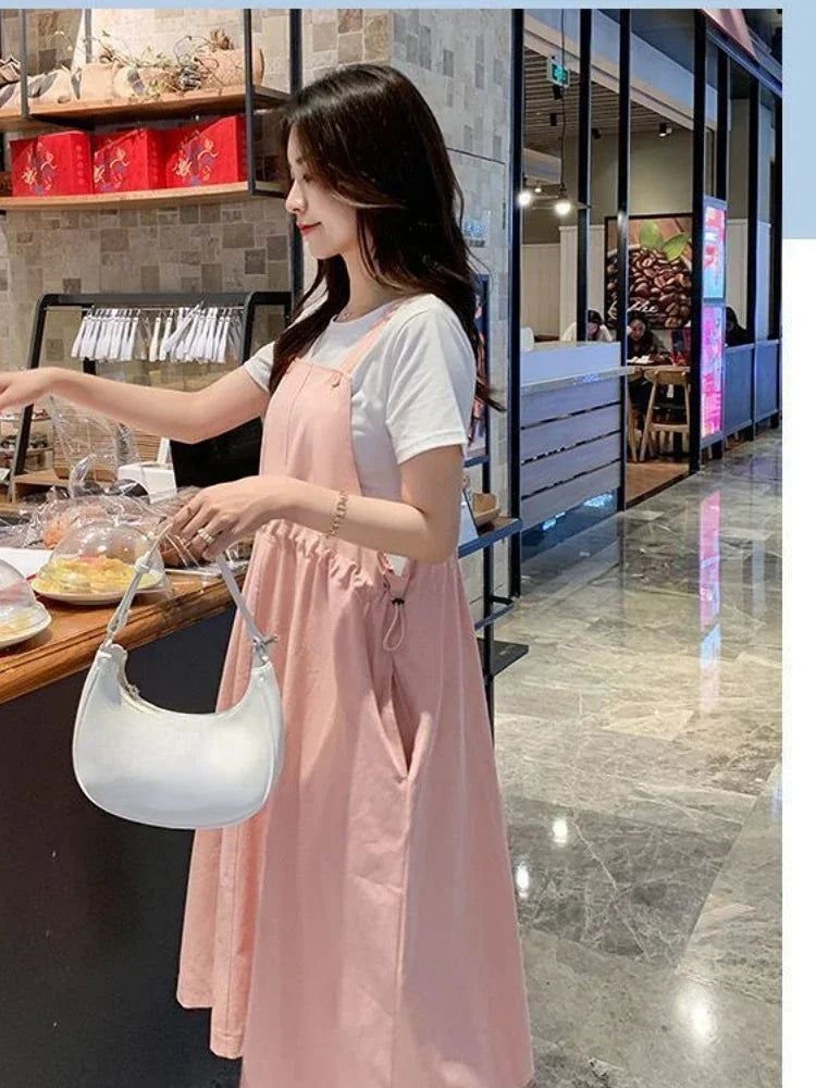 Model wearing a pink loose fit maternity dress in a café, ideal for holiday photography outfits.