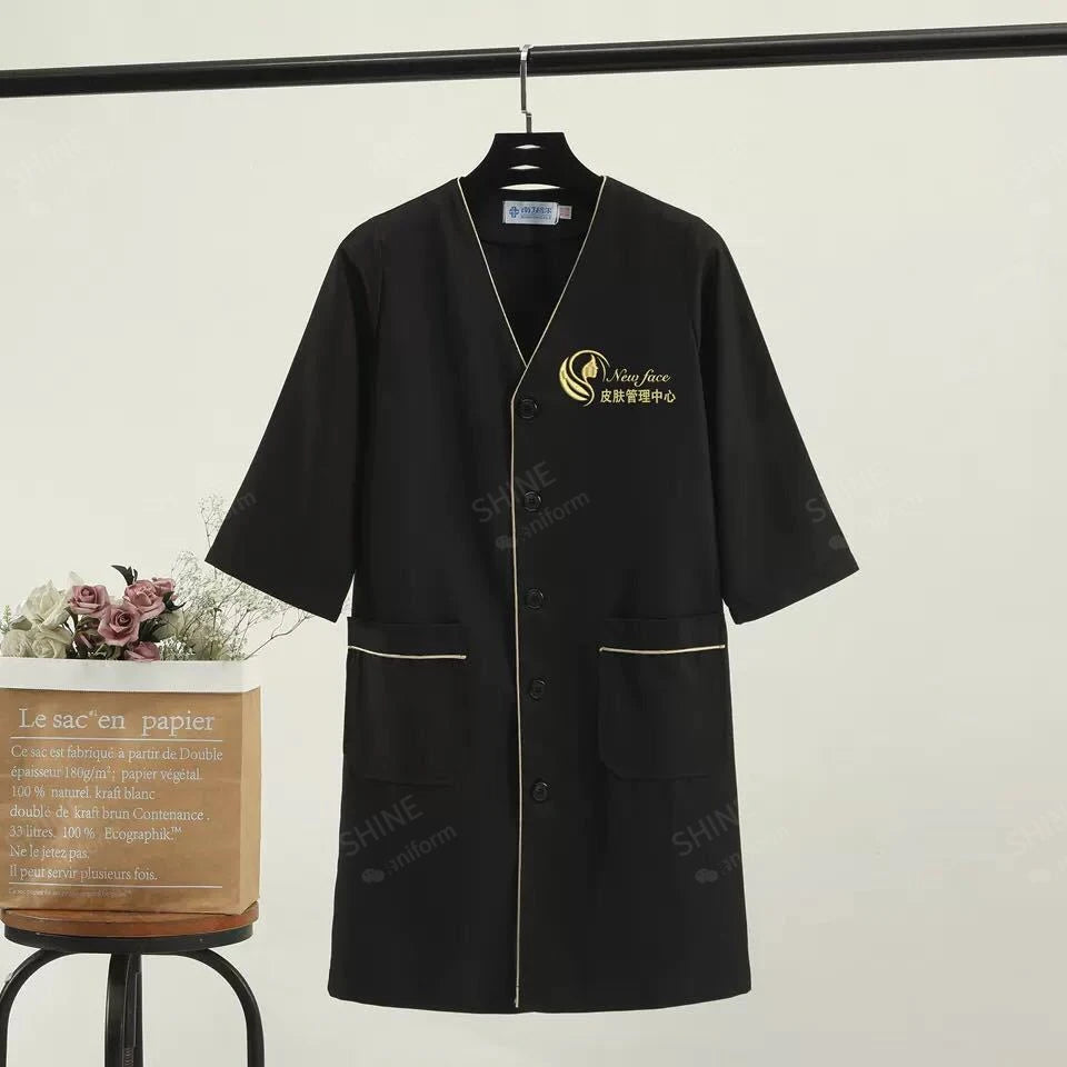 Black beauty uniform with logo, short sleeves, stylish design, ideal for salons and spa professionals.