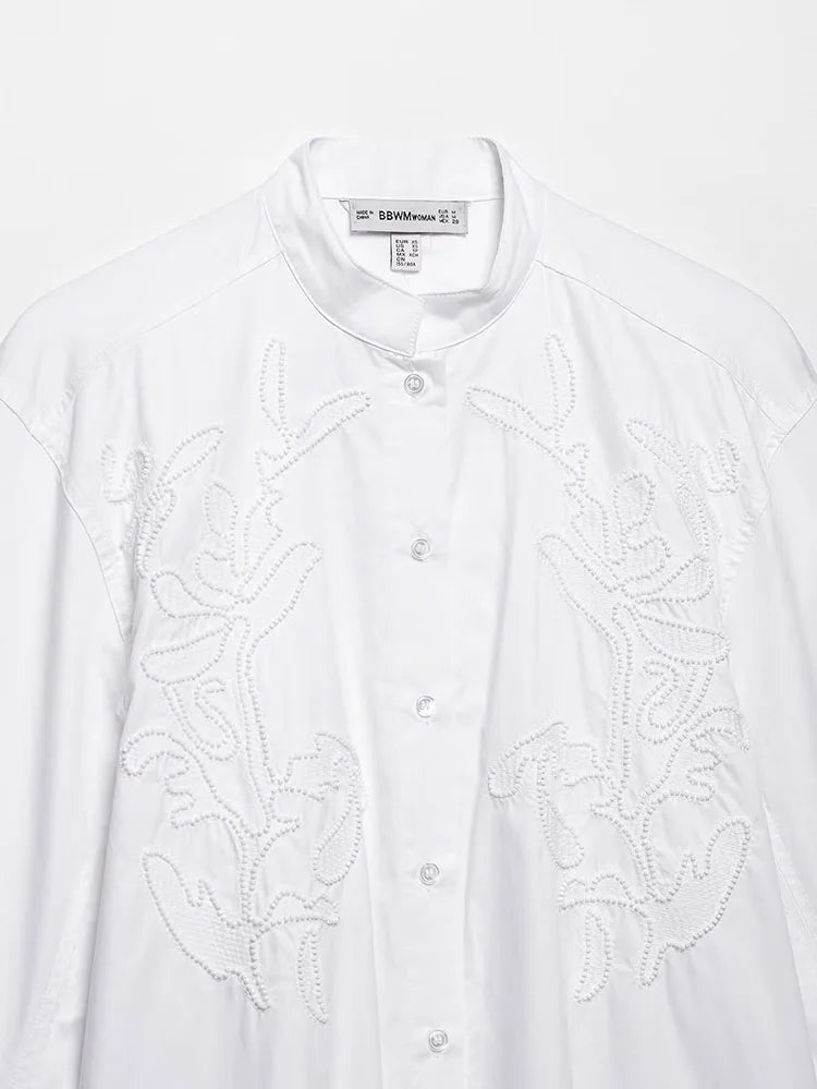 Elegant white embroidery shirt with stand collar and button closure, showcasing intricate floral patterns.