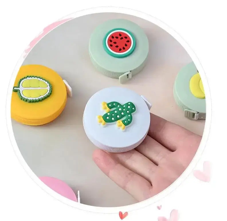 Colorful mini tape measures with cute fruit and frog designs, perfect for kids and fun crafting.