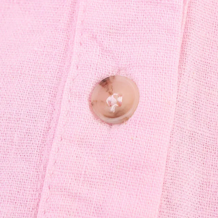 Close-up of a pink button on AsymLinen™ wide sleeve linen shirt fabric.