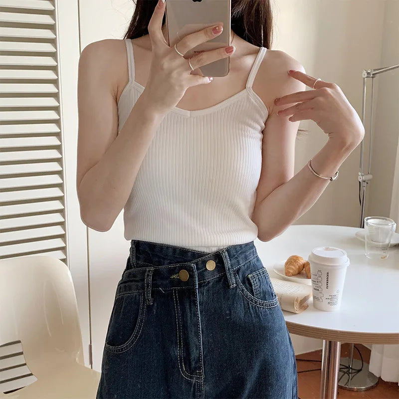 Woman wearing a white ribbed tank top and high-waisted denim skirt, showcasing a casual and stylish outfit.