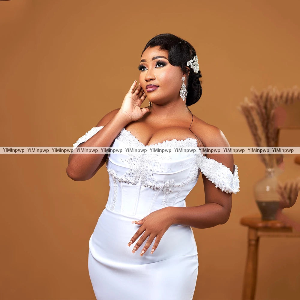 Elegant off-shoulder wedding dress with pearls and detachable train, showcasing a stunning mermaid silhouette.