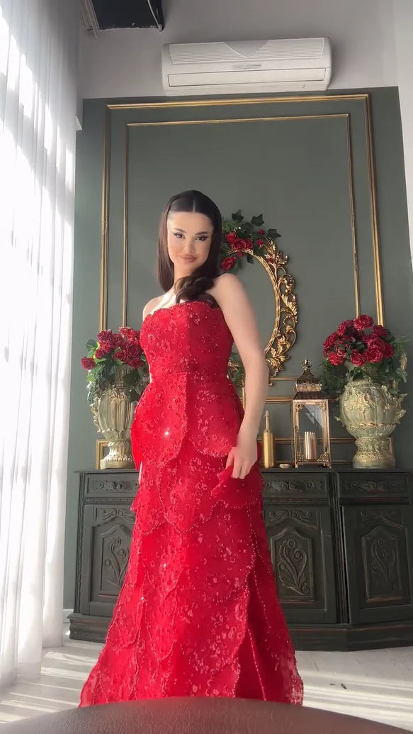 Stylish model wearing a floor-length red beaded engagement dress with a tiered skirt and strapless neckline.