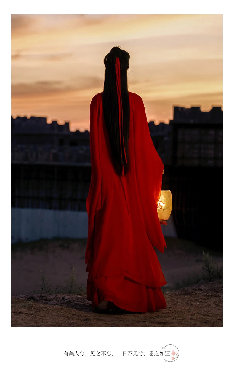 Woman in a flowing red Hanfu dress holding a lantern at sunset, embodying traditional Chinese elegance.