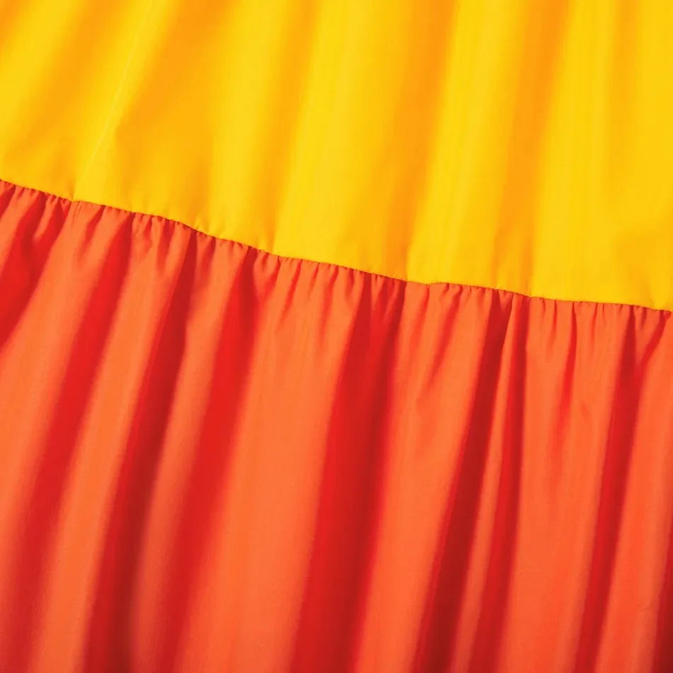 Close-up of vibrant yellow and orange fabric with pleated design, ideal for summer maternity dresses.