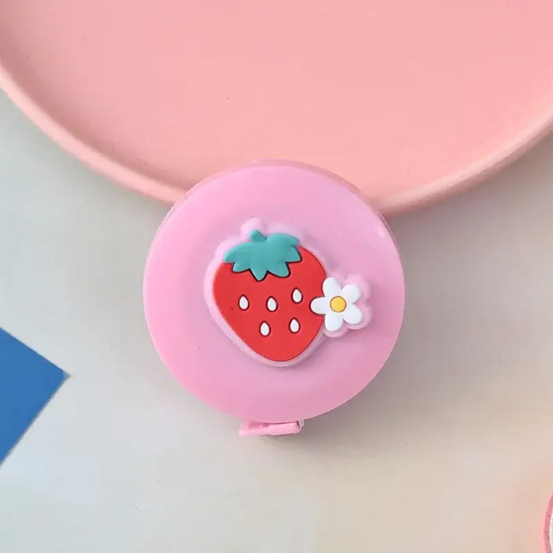 Cute pink measuring tape with strawberry design and flower detail, perfect for kids' crafts and school supplies.
