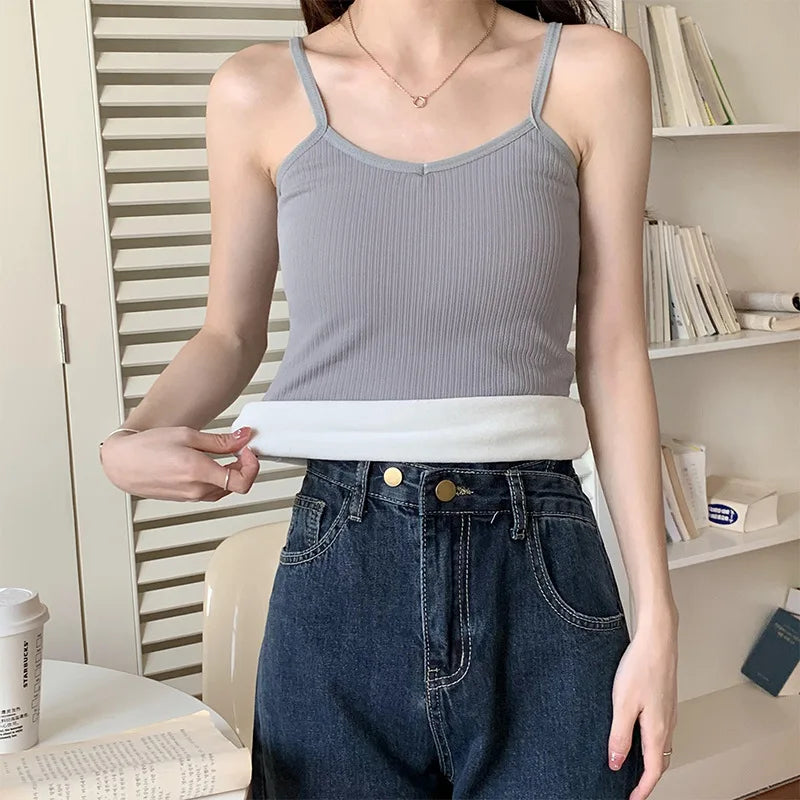 Woman wearing a gray ribbed crop tank top with a contrasting hem, paired with high-waisted jeans.
