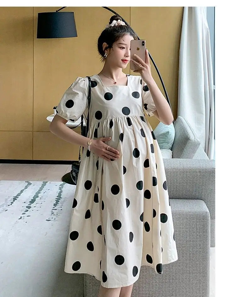 Model wearing a polka dot loose maternity dress in a bright indoor setting, showcasing a comfortable and stylish summer outfit.