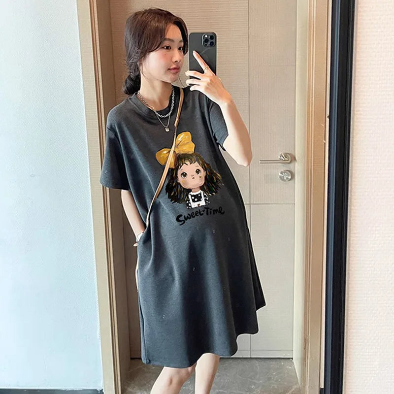 Casual maternity T-shirt dress with cartoon design, boat neck, knee-length, perfect for summer, worn by a woman.