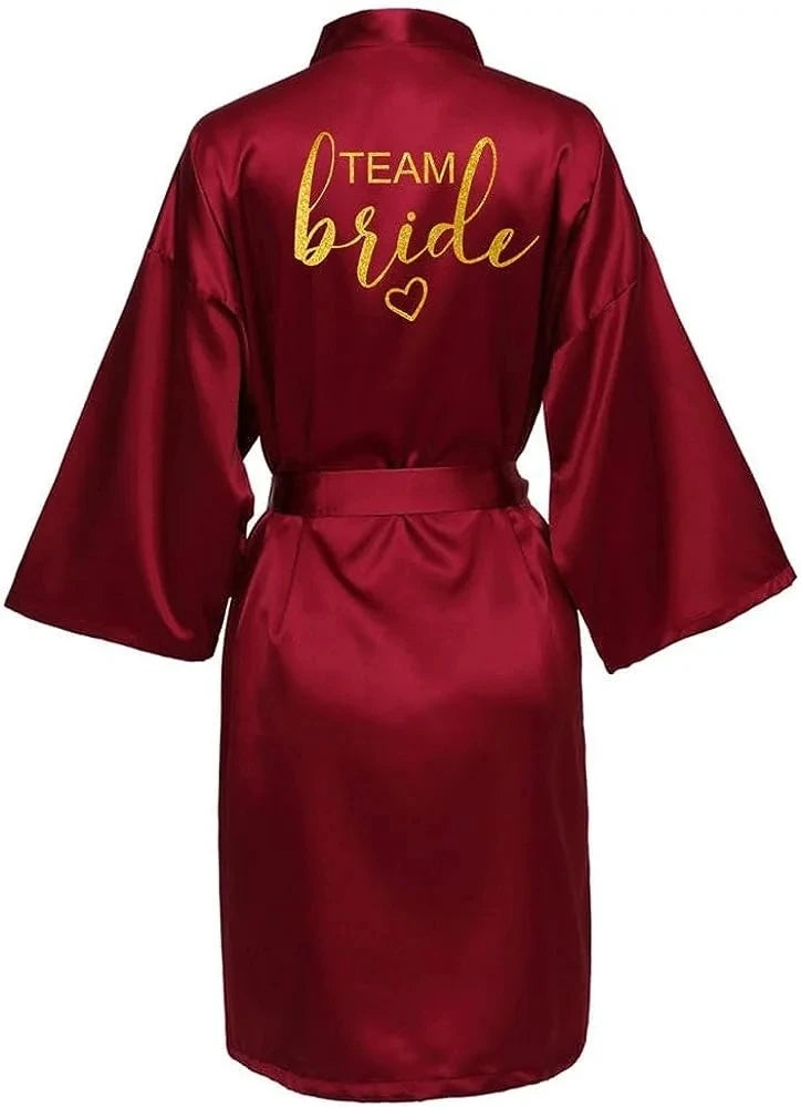 Maroon satin robe with gold 'TEAM BRIDE' print, perfect for bridal parties and celebrations.