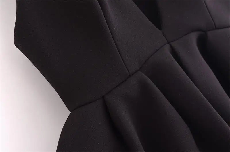 Close-up of elegant black fabric detail from a V-neck women tank top, showcasing its pleated design and smooth texture.