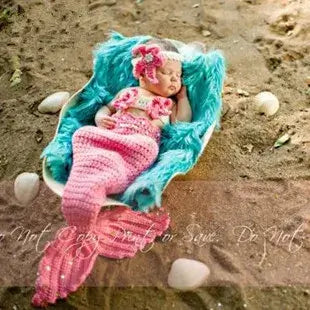 Adorable unisex baby in a pink mermaid costume lying on a fluffy blanket, perfect for 0-6 months clothing.