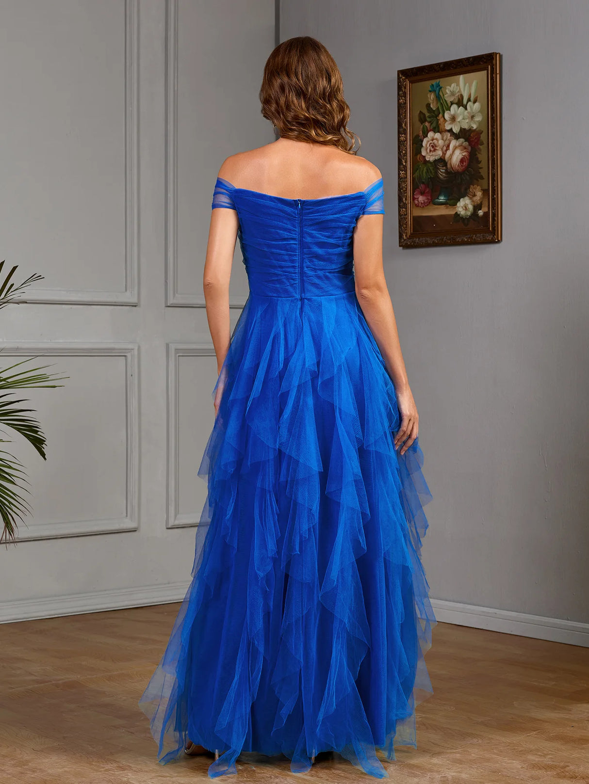 Back view of a stunning blue multi-layered gown, featuring an off-the-shoulder design and elegant ruffles.