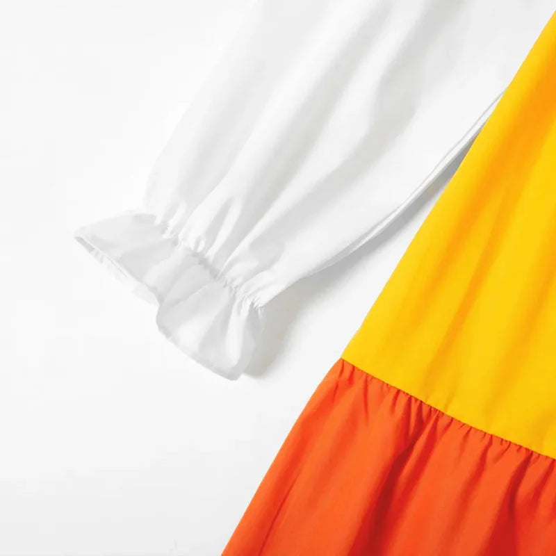 Close-up of the long sleeve and colorful pleated hem of a V-neck maternity dress in vibrant yellow and orange.