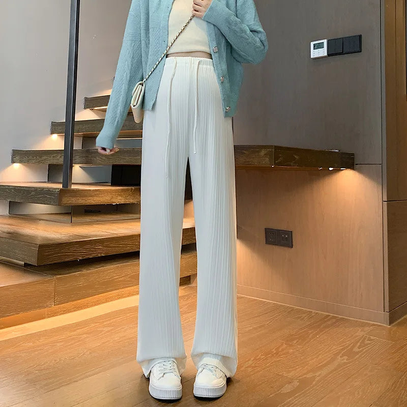 Wide-leg maternity pants in white, featuring drawstring waist and relaxed fit, styled with a casual top and sneakers.