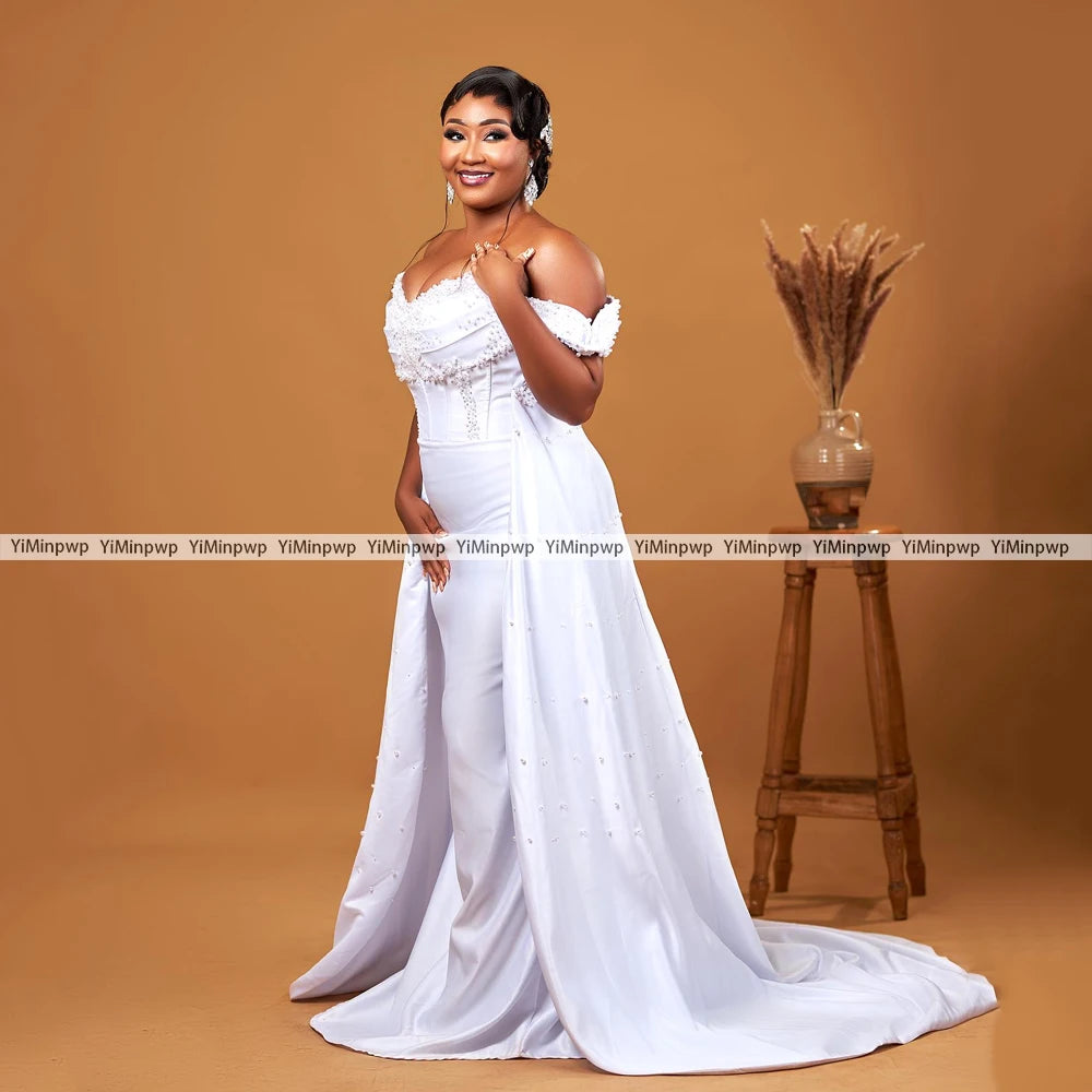 Elegant off-shoulder wedding dress with detachable train, adorned with pearls, perfect for brides and special occasions.