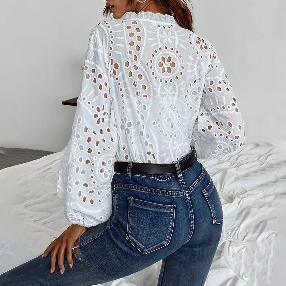Woman wearing the LaceWhisper™ hollow out white lace shirt with long sleeves, paired with jeans.