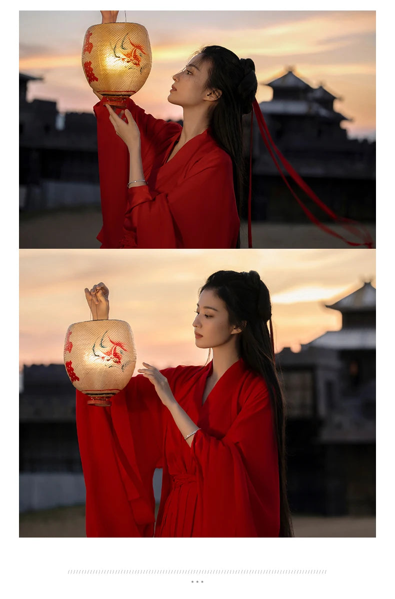 Woman in a red Hanfu dress holding a lantern, showcasing Chinese traditional fashion at sunset.