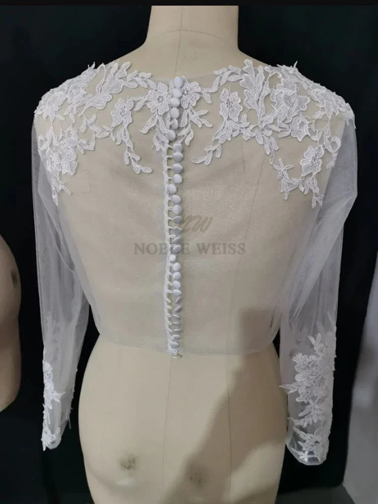 Lace bridal bolero with long sleeves and detailed appliques, showcasing elegant back design and button closure.
