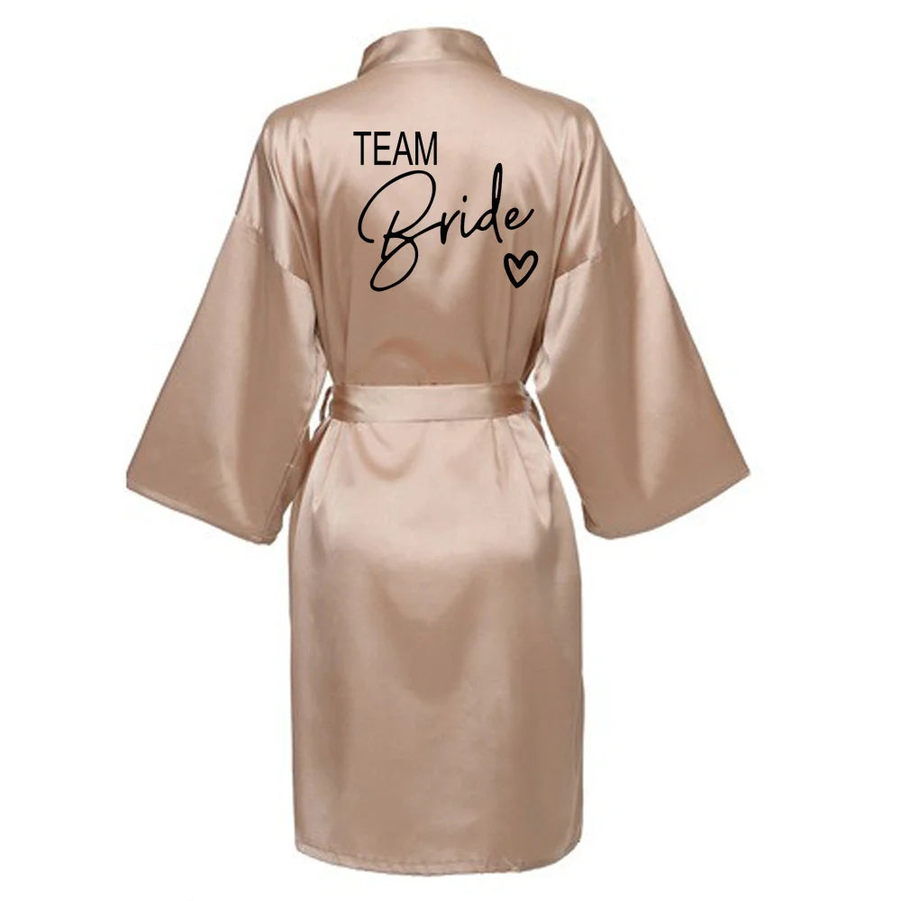 Team Bride satin robe in soft pink with elegant lettering on the back, perfect for bridal parties.
