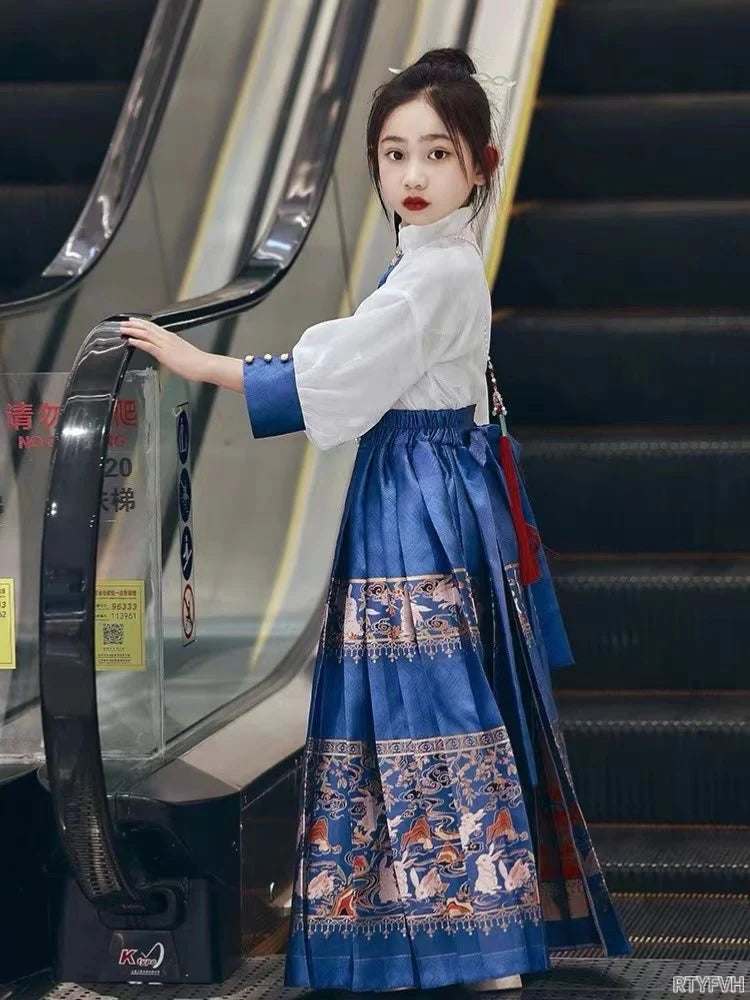 Young girl in a beautiful blue embroidered hanfu dress, posing by an escalator in a modern setting.