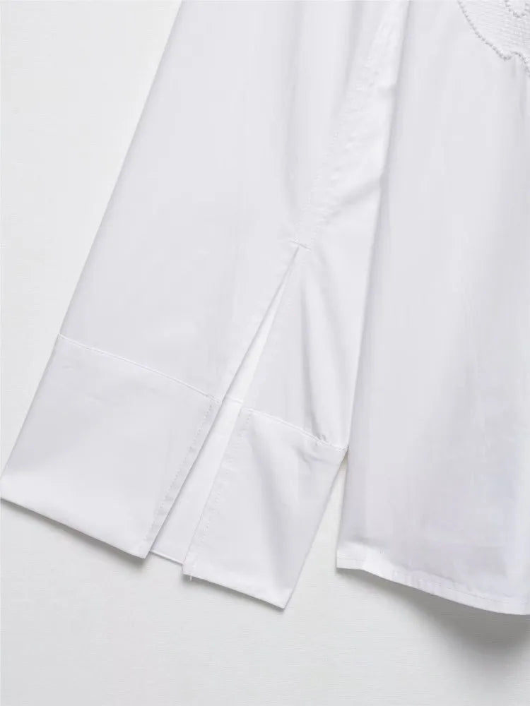Close-up of elegant white embroidered shirt sleeve with slit detail, showcasing chic Korean style.