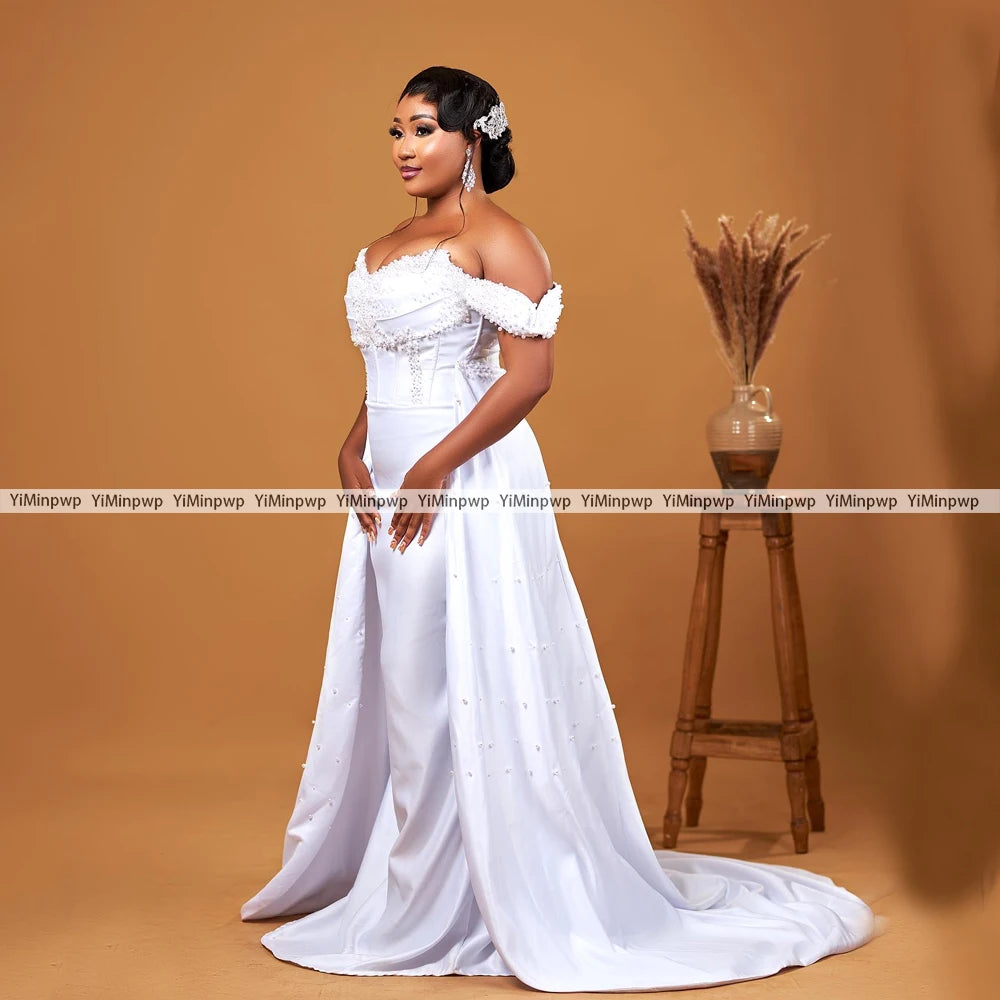 Elegant off-shoulder wedding dress with detachable train and pearl decoration, showcasing a floor-length mermaid design.