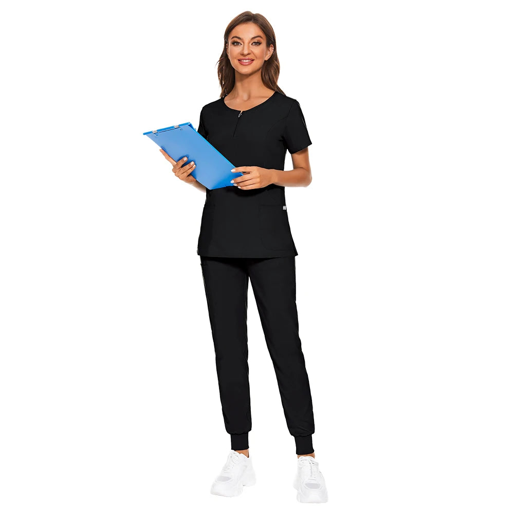 Woman wearing black nursing work uniform with zipper V-neck and matching pants, holding a blue clipboard.