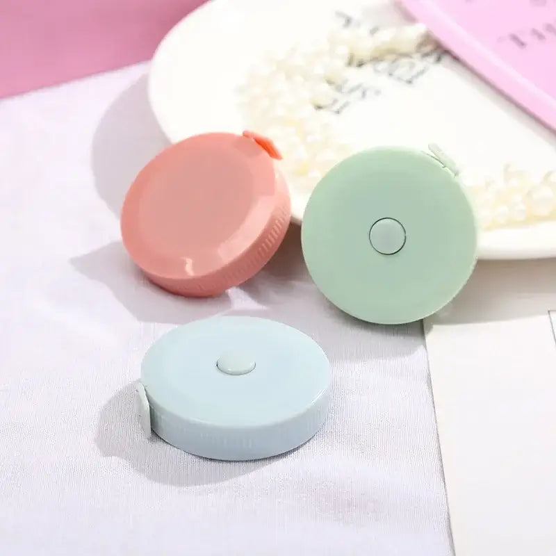 Three colorful mini tape measures in pink, green, and blue placed on a table for easy styling and measurement.