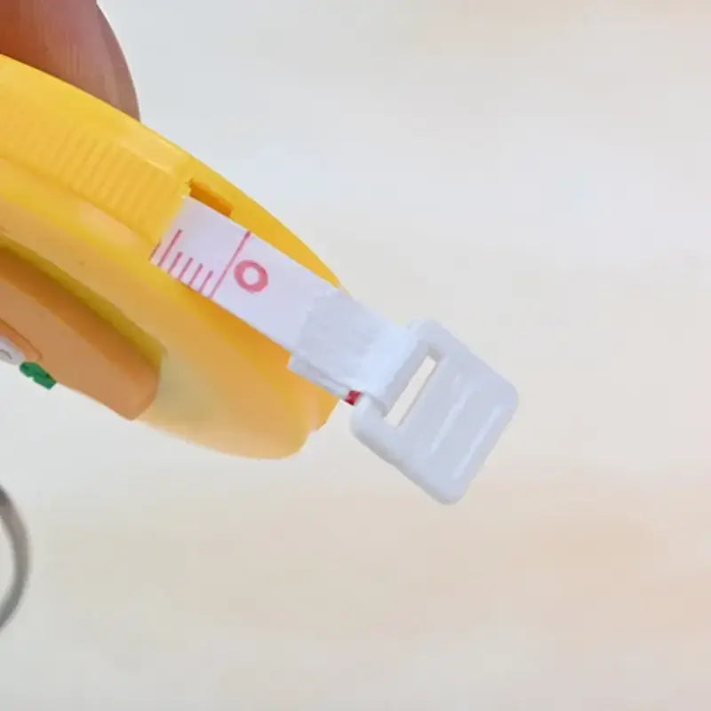 Close-up of the tape measurement from a 150cm cute mini baby height ruler, featuring a yellow casing and a white measuring strip.