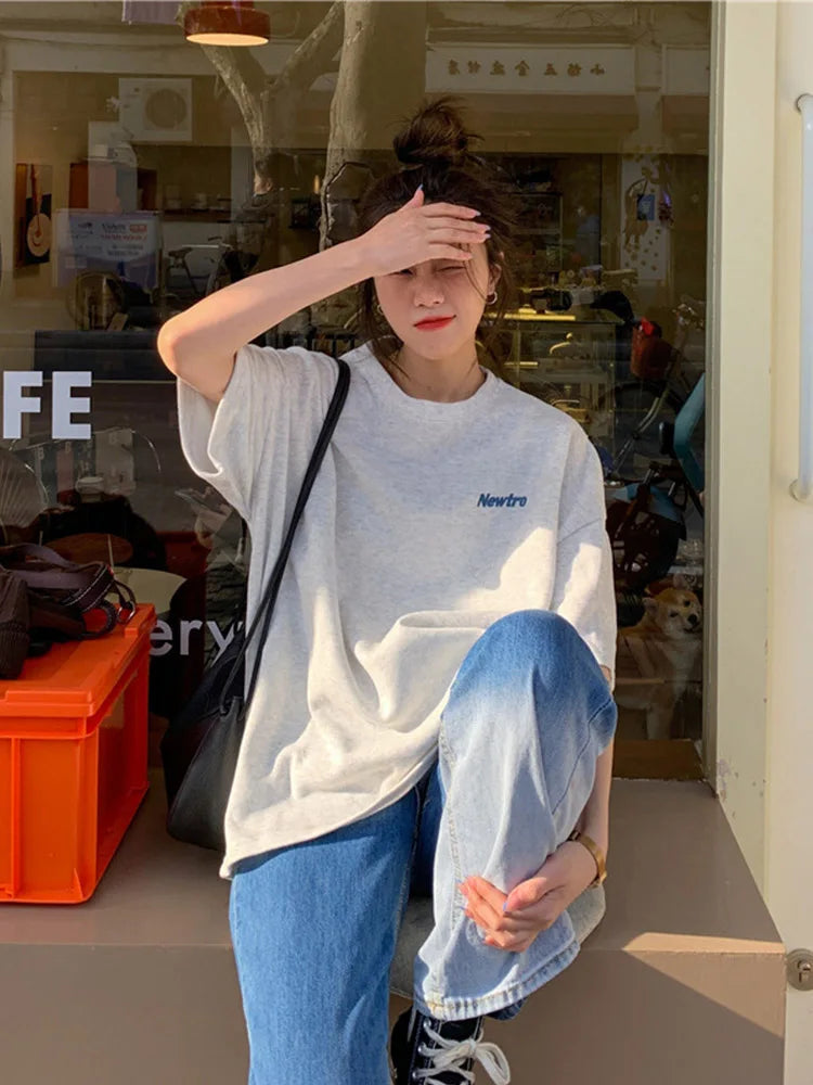 Oversized Harajuku streetwear tee in gray, worn casually with blue jeans, perfect for a relaxed day out.